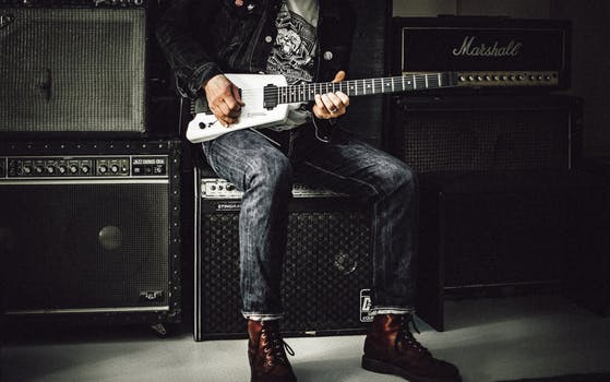 Guitarist from best wedding bands leaning on amp playing white electric guitar.